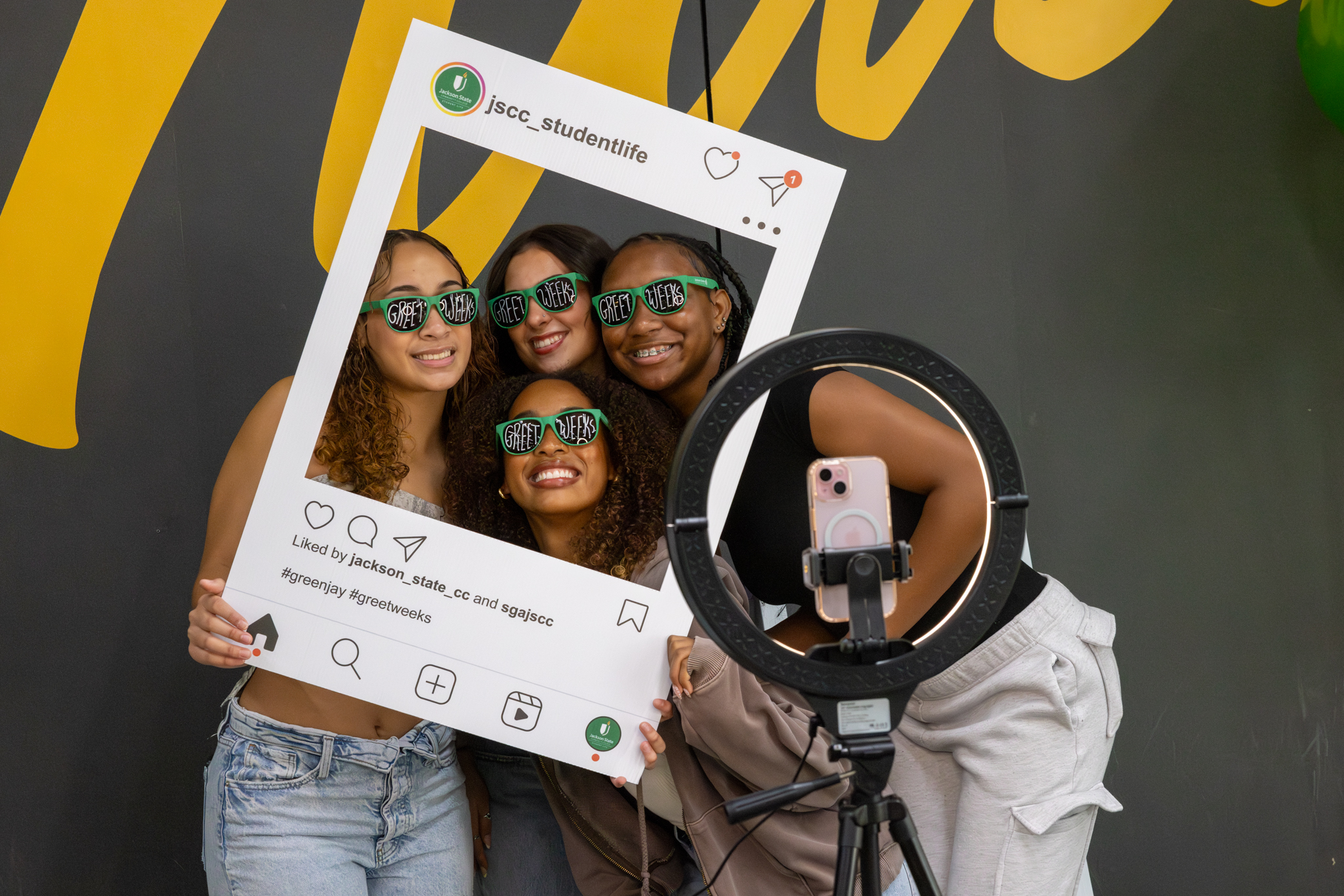 Students pose in front of a ring light with a JSCC Student Life photo frame.