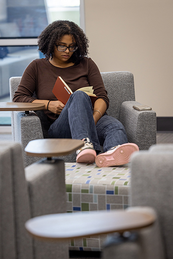 A student reads a book while sitting in the newly renovated JSCC Learning Commons.