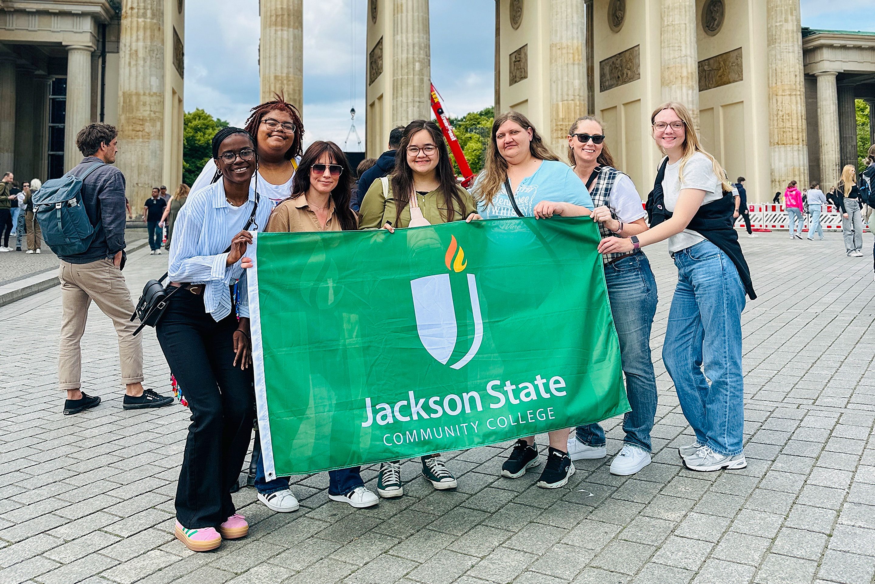 A group of students with JSCC's Global Learning program pose with a JSCC flag during one of their overseas trips.
