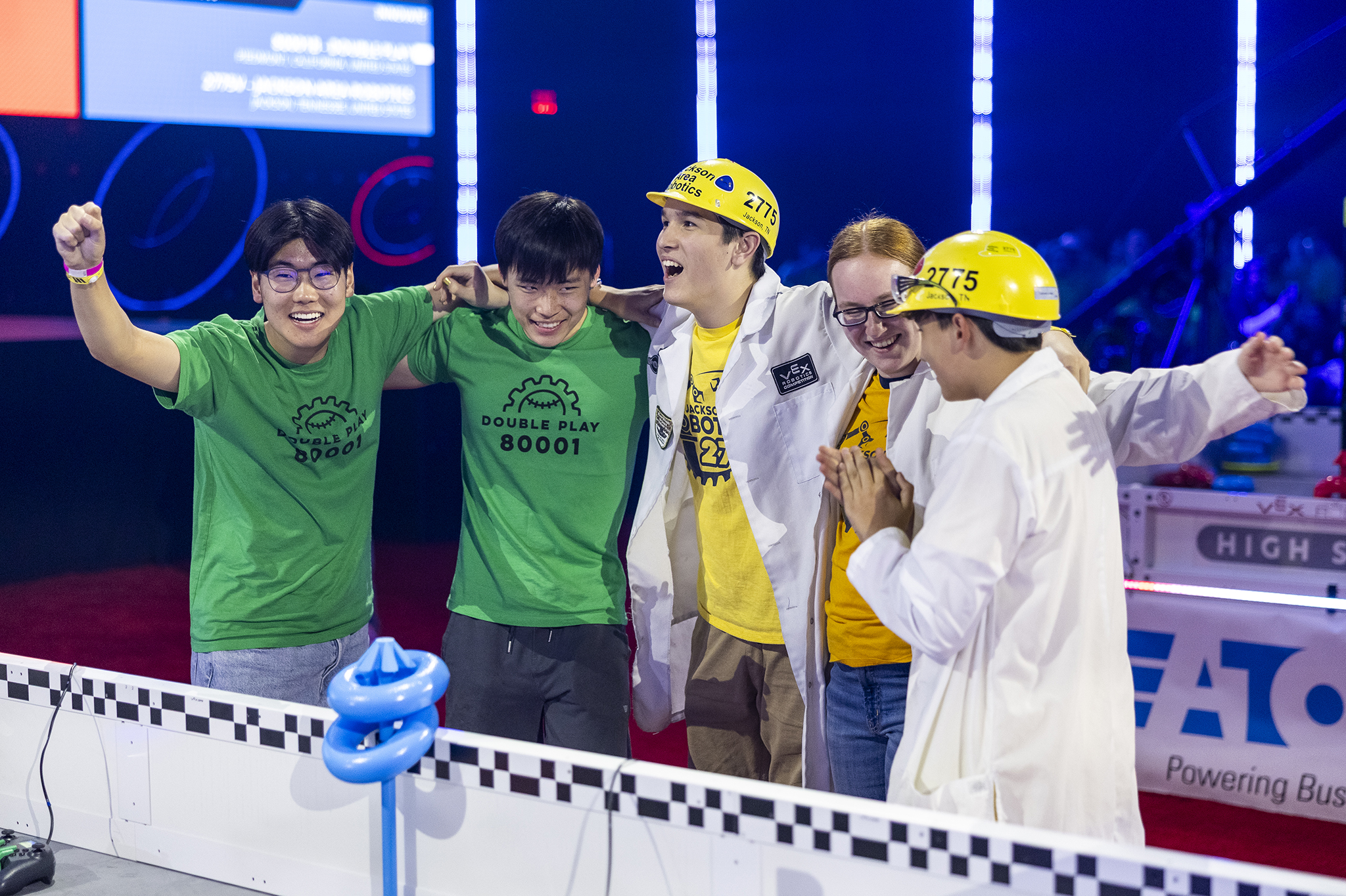 Photo of students competing at the VEX World Championships huddled and excited with their teammates.