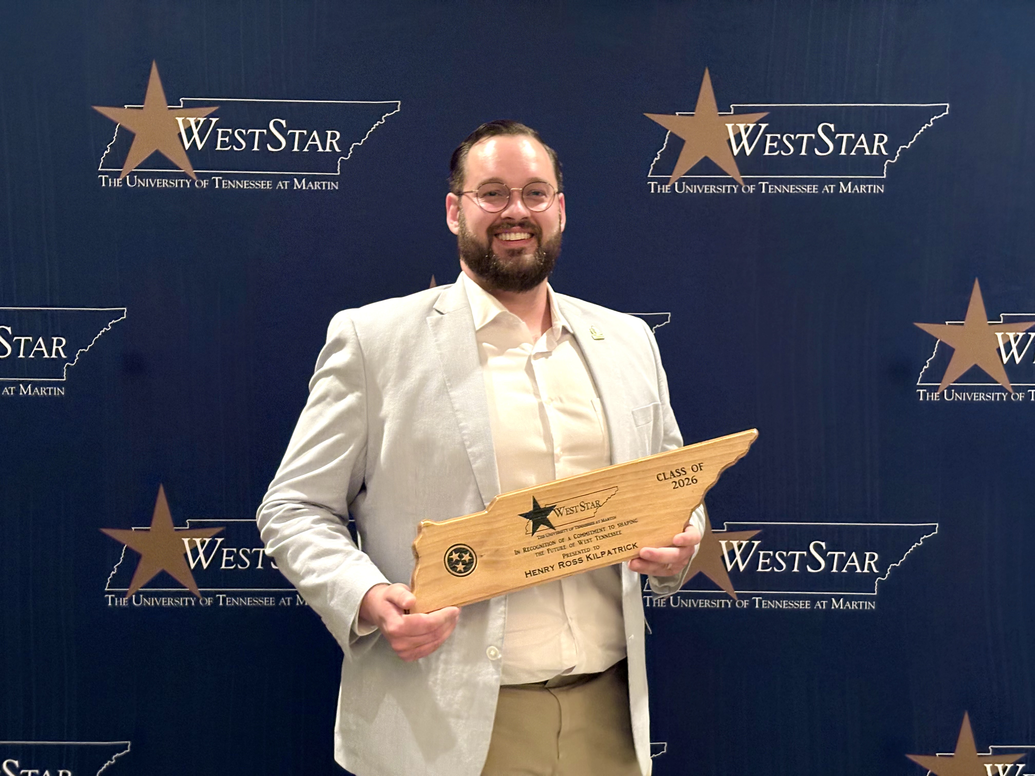 Henry Kilpatrick poses with a Tennessee shaped award in front of a backdrop during the 2026 WestStar Graduation at the University of Tennessee at Martin.